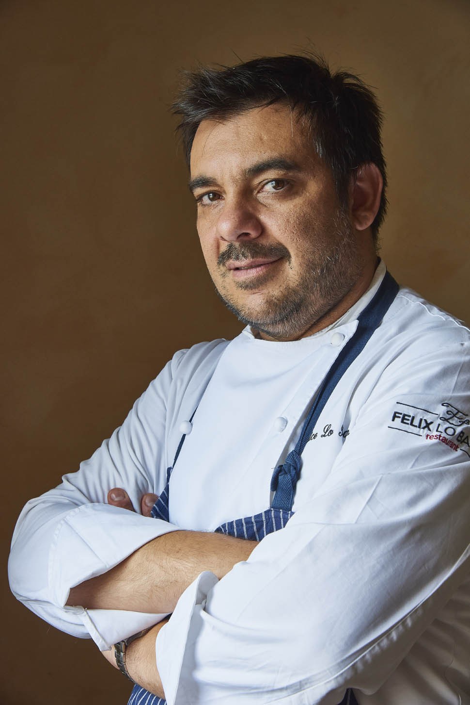 Ritratto di Felix Lo Basso in giacca da chef, a braccia conserte